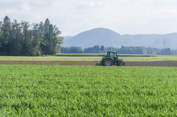 Fototapeta premium Agricultural tractor plowing field in Slovenia.