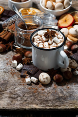 hot chocolate with marshmallows and sweets on wooden table, vertical