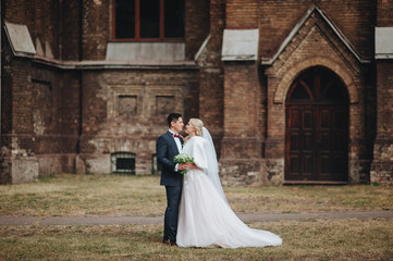 The bride blond and groom stand on the background of the catalytic church. Catholic temple. Wedding concept. 