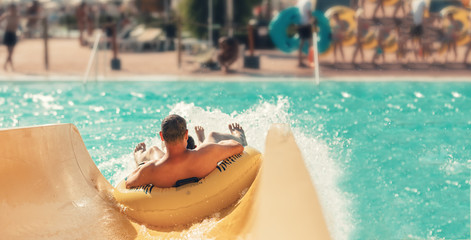 Cool people having fun on the water slide with friends and familiy in the aqua fun park glides...