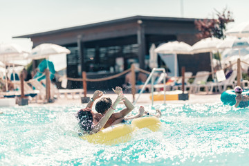 Young people having fun on the water slide with friends and familiy in the aqua fun park glides,...