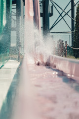 Young people having fun on the water slide with friends and familiy in the aqua fun park glides,...