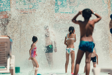 Kids playing with water in the the aqua fun park having fun, they are happy and water splashes are...