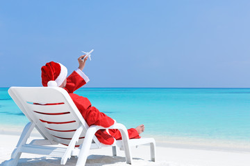 Obraz premium Santa Claus relaxing on sun bed, Christmas card