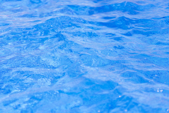 Close-up of crystal-clear water with sunshine in the swimming pool, background, texture. Swimming conception. Shallow depth on focus.