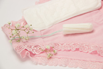 Hygienic tampon and sanitary napkin for every day with panties with green flowers on a white background