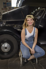 Fototapeta na wymiar girl in blue overalls sitting near a black antique car