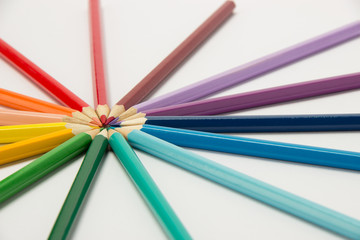 Fototapeta premium A group of pencils folded in rainbow colors in a circle on a white background