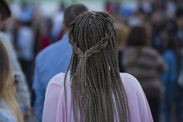 Beautiful young woman with a hairdress dreadlocks collected in a ponytail, sunny open, with no face from the back