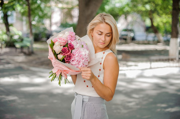 Fototapeta premium Blond woman holding a beautiful composition of flowers