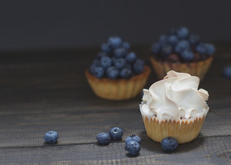 Cupcake with blueberries and a delicate white cream on a black background