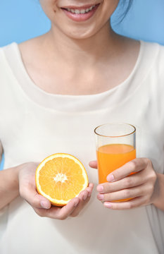 Woman holding sliced orange with Orange juice.