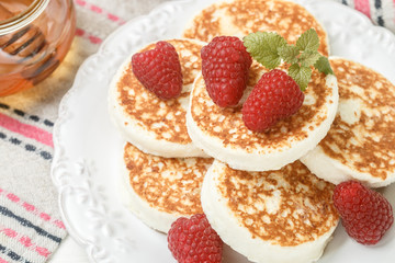 Homemade cheese pancakes with honey and fresh raspberries. Traditional Tasty and healthy Breakfast. Selective focus