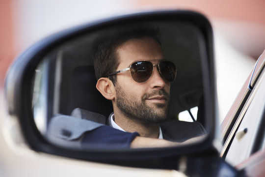 Shades driver in reflection in rear view car mirror