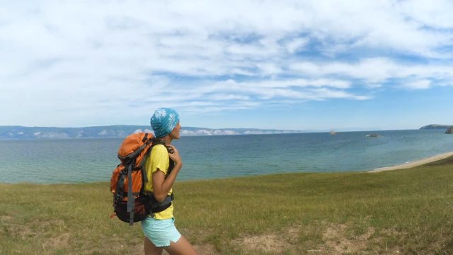woman hiker trekking on walking along blue lake. Wearing backpack. Healthy lifestyle Caucasian girl in Siberia in summer, Russia