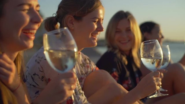 Young happy girls talking drinking wine seaside sunrise rapid slow motion