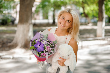 Fototapeta premium Smiling woman holding a pretty composition of flowers and toy