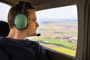 Portrait of young adult passenger sitting in private air plane and looking out window