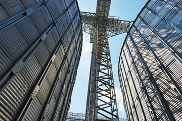 Agricultural Silos. Building Exterior. Storage and drying of grains, wheat, corn, soy, sunflower against the blue sky with white clouds