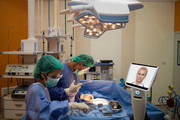 doctor surgery patient in operating room in hospital and talk ,consult with specialist doctor by telepresence robot during emergency. robot(artificial intelligence) technology for better,efficiency