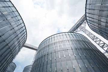 Agricultural Silos. Building Exterior. Storage and drying of grains, wheat, corn, soy, sunflower against the blue sky with white clouds © standret