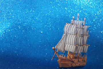 Columbus day concept with old ship over blue glitter background