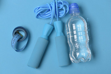 Skipping rope in cyan color on blue background, top view.