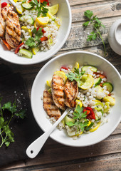 Pearl barley with seasonal garden vegetables and grilled chicken on wooden background, top view. Healthy balanced food concept