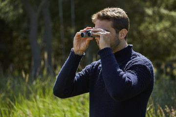 Fototapeta na wymiar Scrutinizing spy guy looking through binoculars
