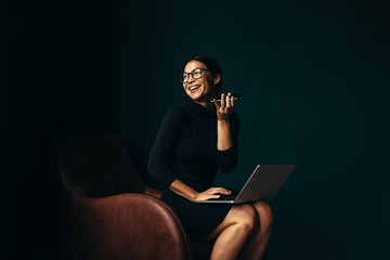 Businesswoman with laptop talking on mobile phone