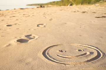 Fototapeta na wymiar Prints of emoji smile in the sand on the beach of the Baltic Sea in summer: summer is almost gone, waiting for autumn.