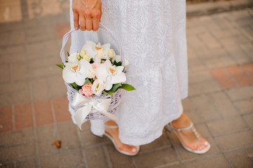 Woman in white dress holding a wicker basket of flowers