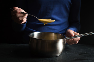 Spoon in hand with base sauce roux on blue background