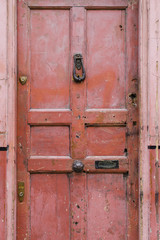 Old vintage english style red salmon pink front door with age related marks brass knocker doorknob banham security lock and letterbox