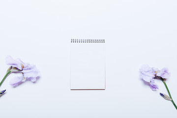 Notepad and blue flowers on a white table