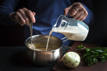 Milk from the jug is poured into a base sauce for making bechamel