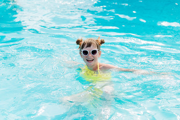 Beautiful girl in a swimsuit swims in the pool