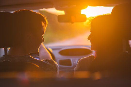 The happy couple sitting in a car on the background of the sunset