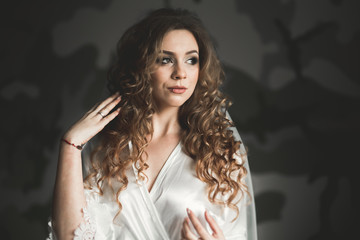 Fototapeta premium Gorgeous bride in robe posing and preparing for the wedding ceremony face in a room