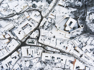 Aerial view of small town with hills in winter.
