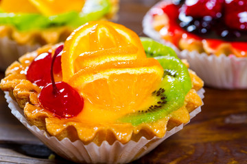 Delicious fruit cake on brown wooden background with strawberries, cherries, currants and raspberries. Beautiful, delightful and healthy desserts