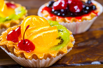 Delicious fruit cake on brown wooden background with strawberries, cherries, currants and raspberries. Beautiful, delightful and healthy desserts