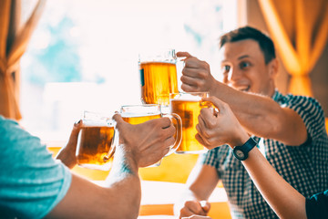 Friends toasting with glasses of light beer at the pub. Beautiful background of the Oktoberfest. A...