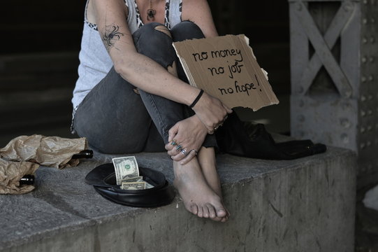 a homeless punk woman begging, holding a sign - no money no job no hope 