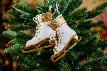 Christmas toys in the form white skates hang on a spruce branch