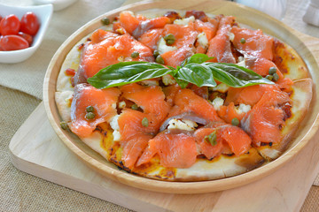Salmon pizza on wooden plate cutting board style