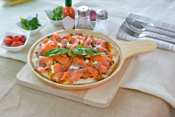 Salmon pizza on wooden plate cutting board style