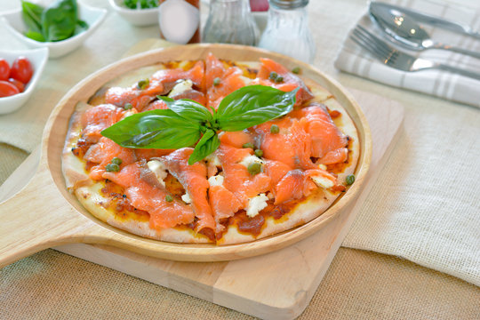 Salmon pizza on wooden plate cutting board style