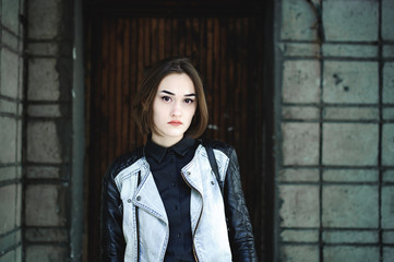 street portrait of a girl student, fashionably dressed in dark clothes, with a black backpack and denim jacket autumn sunny day