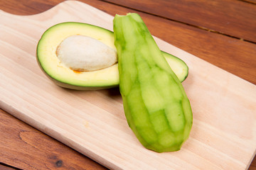 Avocado cut in half, one half peeled, on a wooden background